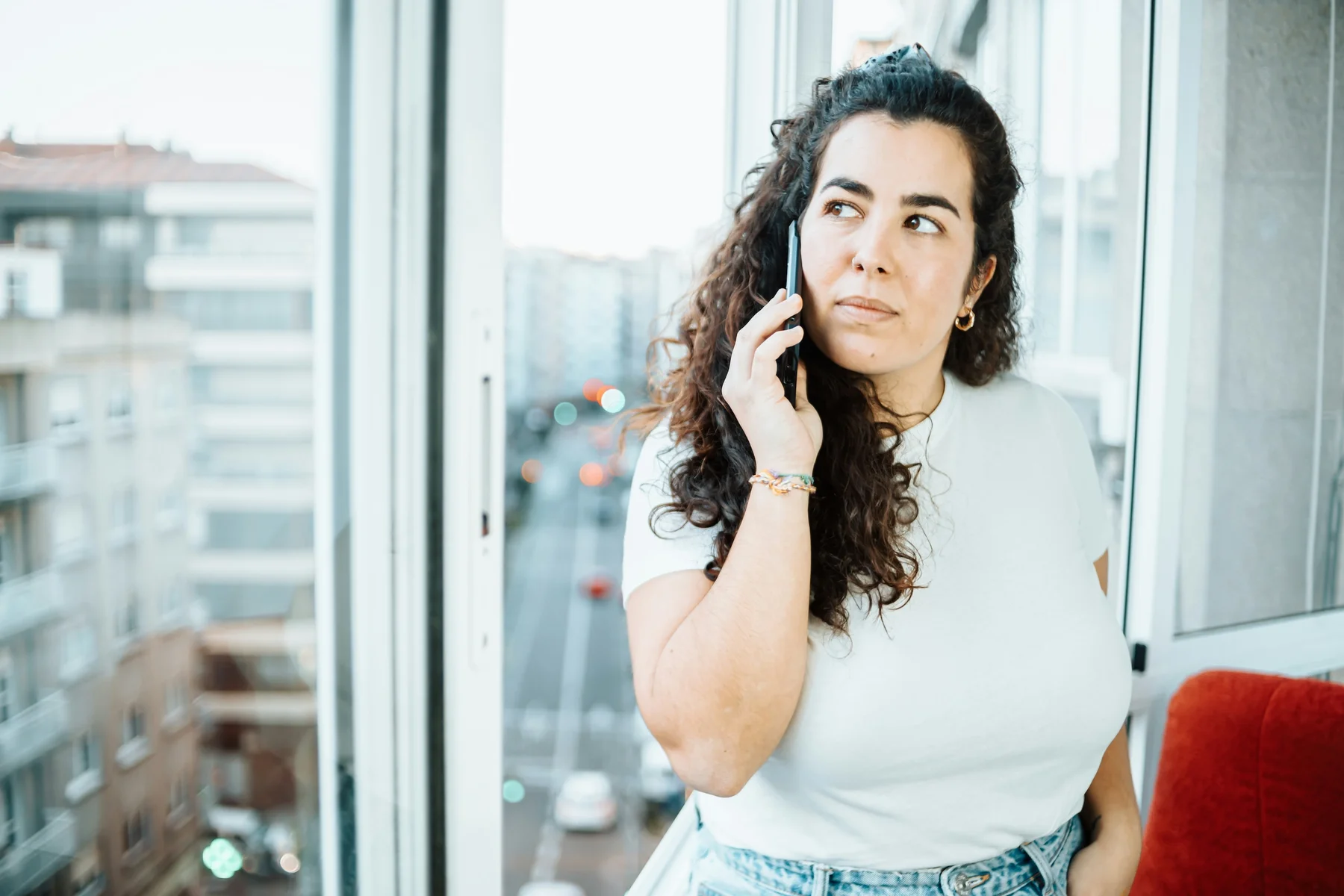 A woman taking time for a phone conversation beside a sunny window